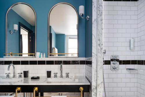a bathroom with two sinks and two mirrors at Hôtel Longemalle in Geneva