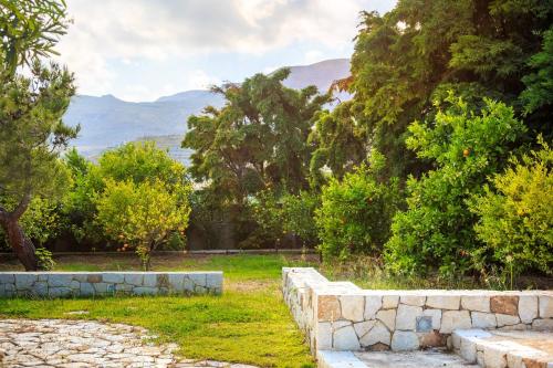 a stone wall with trees and mountains in the background at Amatu Villa (Athena) in Xerokampos
