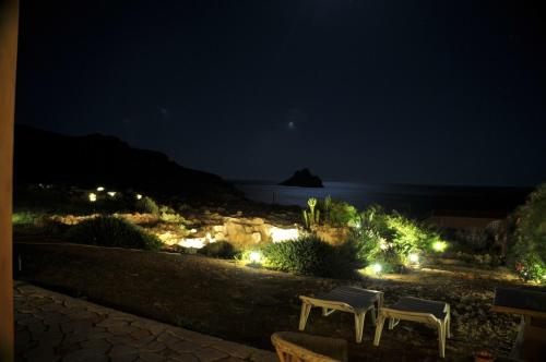 two white chairs sitting on a path at night at Amatu Villa (Athena) in Xerokampos
