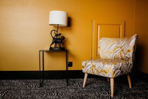 a room with a chair and a lamp on a table at La villa 10 HÔTEL SPA in Étretat