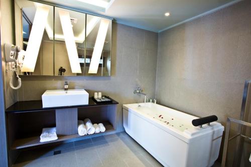 La salle de bains est pourvue d'une baignoire, d'un lavabo et d'un miroir. dans l'établissement Fine Hotel, à Kaohsiung
