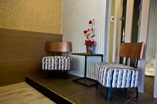 a room with two chairs and a table with a vase of flowers at Fine Hotel in Kaohsiung