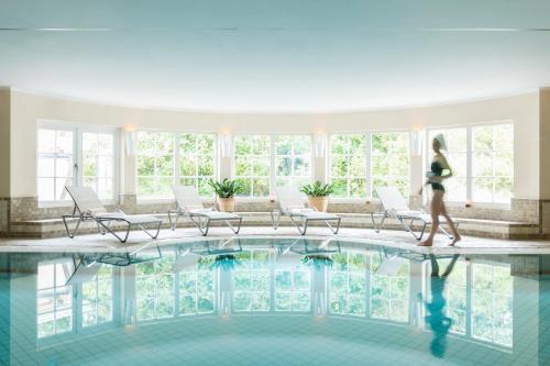 a woman walking in front of a swimming pool at Dorint Strandresort & Spa Westerland/Sylt in Westerland