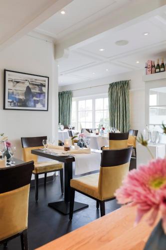 a dining room with tables and chairs and windows at Dorint Strandresort & Spa Westerland/Sylt in Westerland (Sylt)