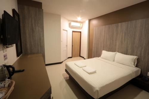 a bedroom with a white bed and a television at Fortune Surin Hotel in Surin
