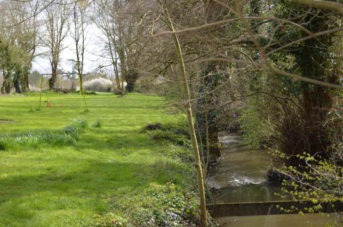 a stream in a park with a field and trees at Gite de Foulleray n 14 in Rouez