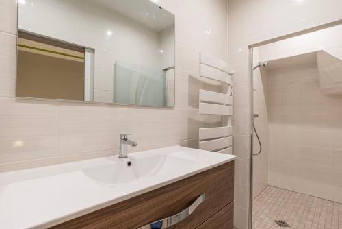 een witte badkamer met een wastafel en een spiegel bij CityCosy Strasbourg - Modern Family Deserte in Straatsburg