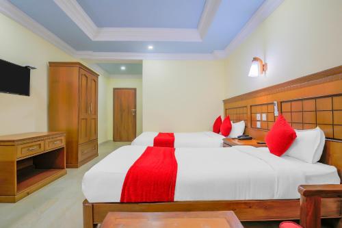 a bedroom with a large white bed with red pillows at Hotel Lacoul Inn in Bhairāhawā