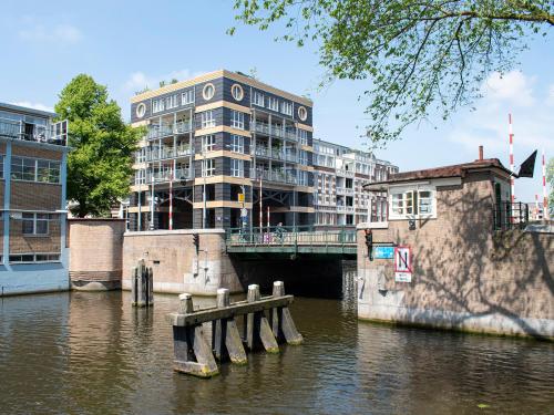 a building on the side of a river with a bridge at SWEETS - Van Hallbrug in Amsterdam