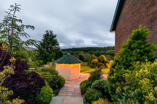 a garden with a white pergola with lights on it at Woodland View Holiday Apartment in Llanwrda