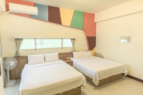 馬公市的住宿－幸福花民宿 ，色彩缤纷的墙壁内的两张床