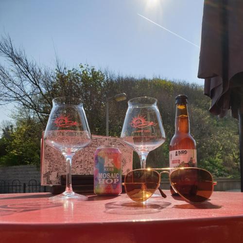three wine glasses and a bottle of beer on a table at Sonnevanck Wijk aan Zee in Wijk aan Zee