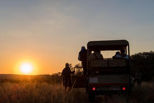 a group of people in the back of a truck in a field at Big Cave Camp in Matopos
