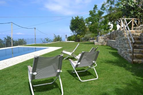 two chairs sitting on the grass next to a pool at Borgo Rosso di Sera - Resort Country Chic in San Lucido