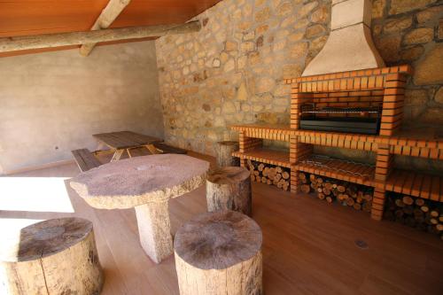 a room with logs and stools and a fireplace at Cascata do Varosa - Turismo Rural in Vila Pouca