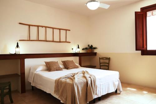 a bedroom with a white bed with a wooden headboard at Agriturismo Francesca Stajano in Alezio