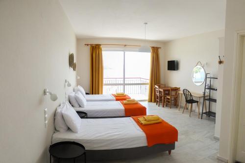 a hotel room with two beds and a dining room at Aphrodite Skiathos in Megali Ammos