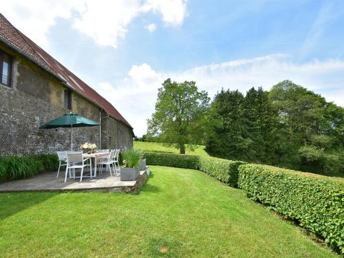 un jardín con mesa y sombrilla en Charming holiday home in a green setting, en Montaigu-les-Bois