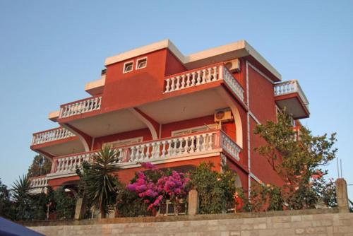 un edificio rojo con balcones y flores en Alvanita Apartments, en Ulcinj