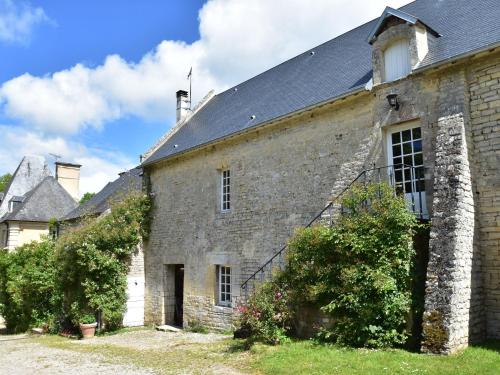 un antiguo edificio de piedra con techo negro en Cozy Holiday Home in Lantheuil with Garden, en Lantheuil