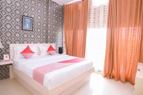 a bedroom with a bed with red pillows on it at Capital O 854 Ub Caisar Hotel in Banda Aceh