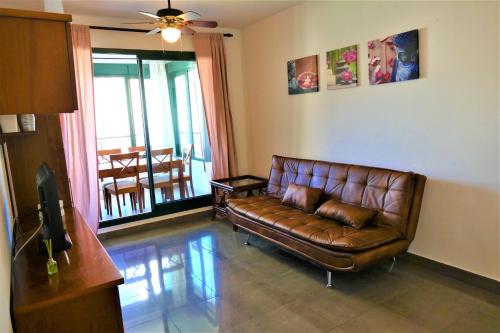a living room with a leather couch and a balcony at Apartamento Parque Torresol in Benidorm