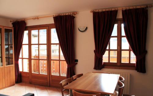 a dining room with a table and two windows at Residence Lucia in Bormio