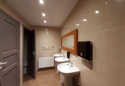 baño con 2 lavabos y TV en la pared en Summer hostel Kaija en Jūrmala