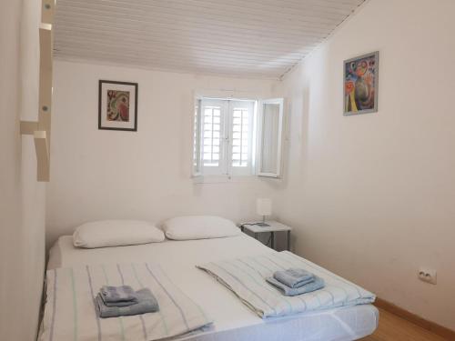 une chambre blanche avec un lit avec des serviettes dessus dans l'établissement Tiny room Piran, à Piran