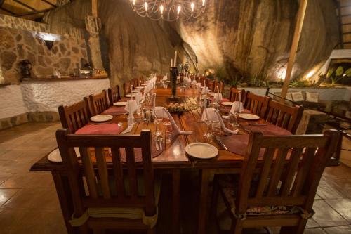 a long wooden table in a room with chairs at Big Cave Camp in Matopos