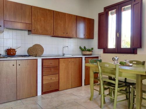 a kitchen with wooden cabinets and a table with chairs at Agriturismo Francesca Stajano in Alezio