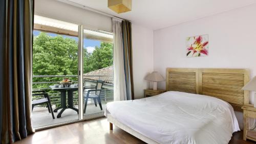 a bedroom with a bed and a balcony with a table at Vacancéole - Le Domaine du Château - La Rochelle / Île de Ré in Lagord