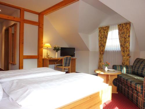 ein Hotelzimmer mit einem Bett und einem Sofa in der Unterkunft Landhaus Müritzgarten Hotel garni in Röbel