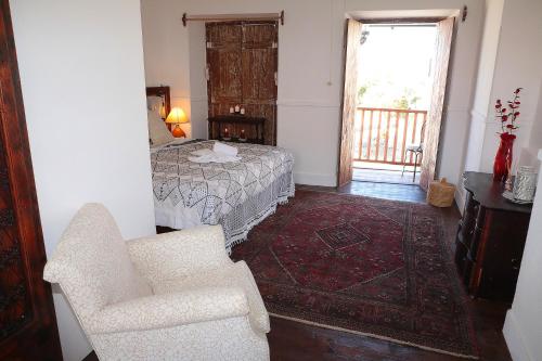 a bedroom with a bed and a chair and a window at Casa Colonial Koenig in São Filipe