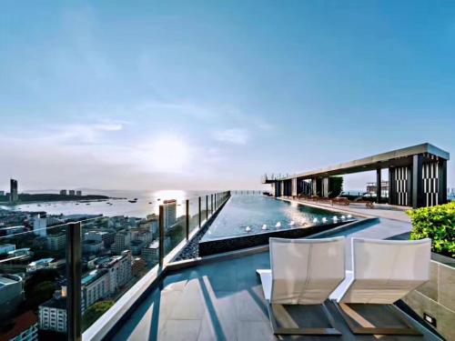 a balcony with white chairs and a swimming pool at the base in Pattaya Central