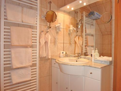 ein Badezimmer mit einem Waschbecken, einem Spiegel und Handtüchern in der Unterkunft Landhaus Müritzgarten Hotel garni in Röbel