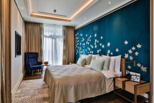 a bedroom with a large bed and a blue wall at Dreamland Golf Hotel Baku in Baku