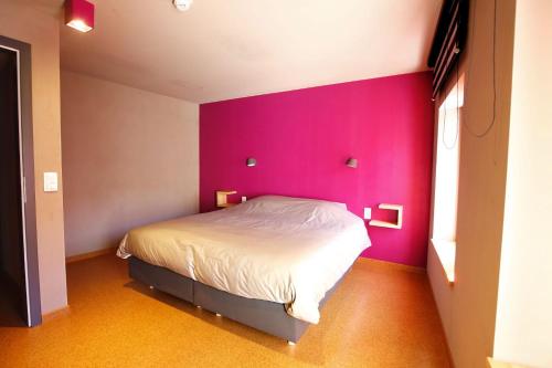 a bedroom with a pink wall and a bed at ô ChÔmière in Stavelot