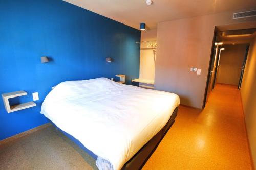 ein Schlafzimmer mit einer blauen Wand und einem weißen Bett in der Unterkunft ô ChÔmière in Stavelot