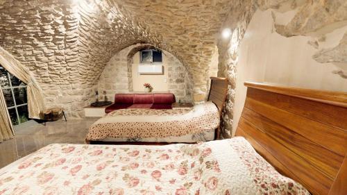 a bedroom with two beds and a stone wall at HEMDAT NEFESH in Safed