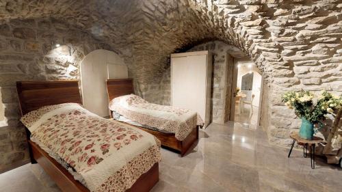 a bedroom with two beds and a stone wall at HEMDAT NEFESH in Safed