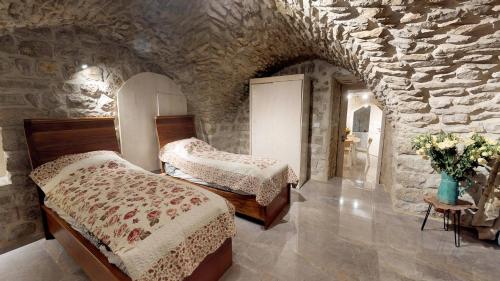 a bedroom with two beds and a stone wall at HEMDAT NEFESH in Safed