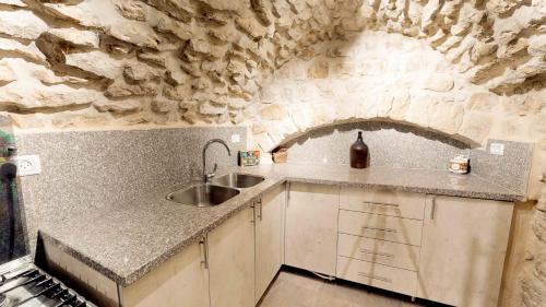 a kitchen with a sink and a stone wall at HEMDAT NEFESH in Safed