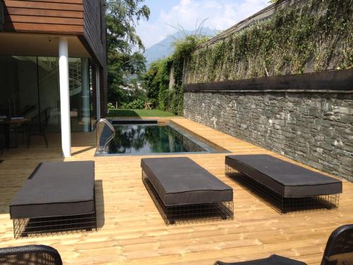 a patio with two cushioned chairs and a swimming pool at Casa Sull'Albero in Malgrate