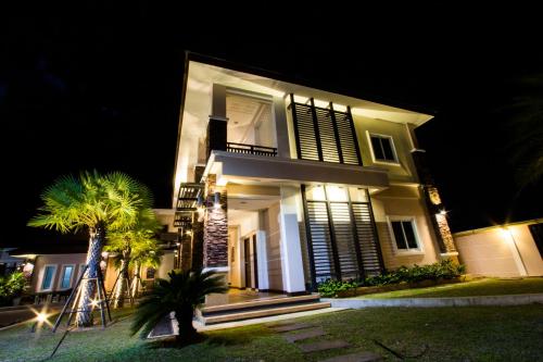 a large white house at night with a palm tree at Fortune Surin Hotel in Surin