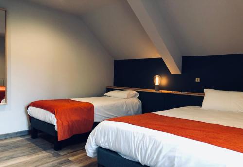 a hotel room with two beds with red and white sheets at Hotel Linette in Aumont-Aubrac