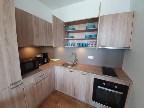 a kitchen with wooden cabinets and a sink and a microwave at Viiking Spa Hotel in Pärnu