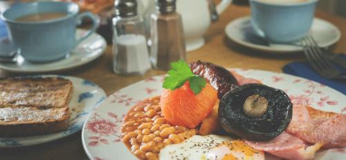 une assiette de petit-déjeuner sur une table avec des tasses de café dans l'établissement The Wellington, à Bristol