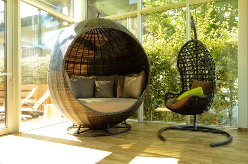 a wicker swing and a chair in front of a window at Aktiv- und Wellnesshotel Gutjahr in Abtenau