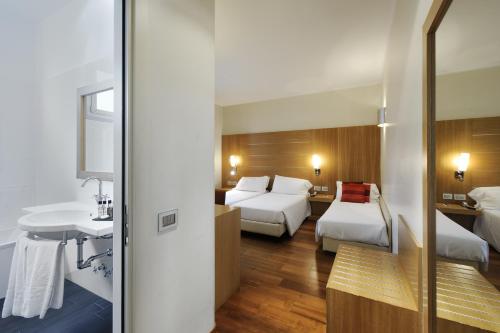 a hotel room with two beds and a sink at Hotel Canada in Milan